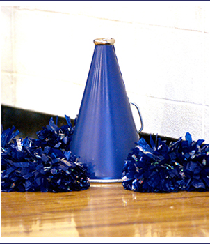 Megaphone and pom poms sit on a gym floor