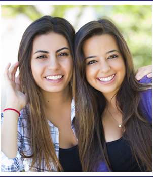 Two smiling students pose together outside